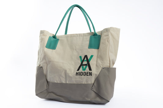 Beige tote bag with green handles and 'Hidden' logo on a white background